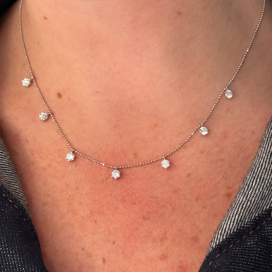Necklace with small diamond-like pendants on a person's neck